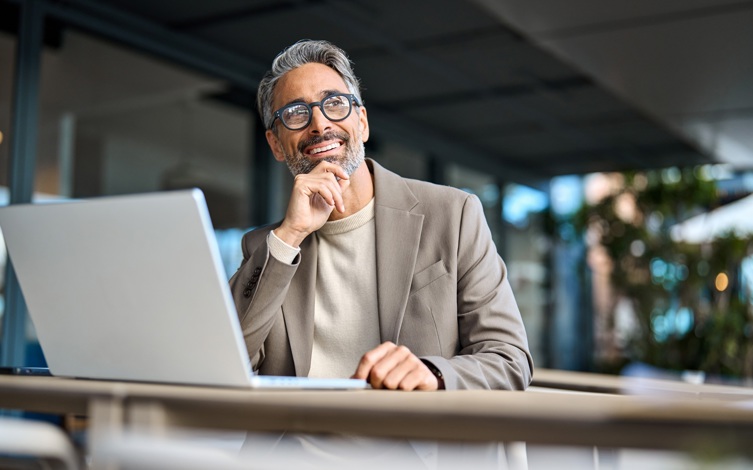 Senior professional using a laptop in a modern business setting, analyzing data or reviewing financial reports, ideal representation of digital transformation and credit risk management in banking